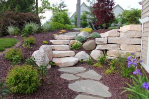boulder retaining wall with stone steps and flagstone path